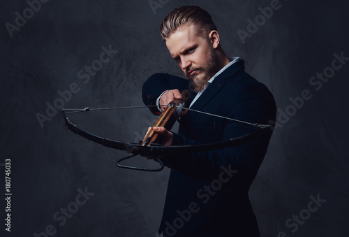 Photographie A man dressed in a suit holds crossbow.