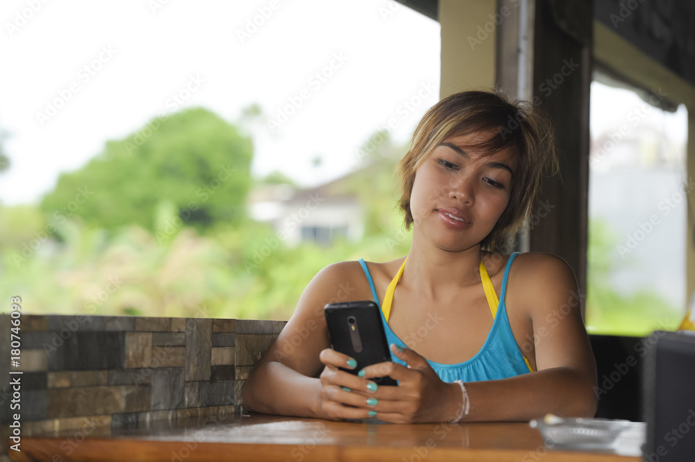 young happy beautiful and attractive Asian woman sitting in coffee shop ...