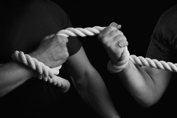 Tug-of-war. Men tighten a rope on a black background