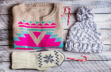 Winter Holiday Knitted Sweater, Mittens, Cap And Christmas Lollipops On White Wooden Background