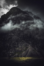 Dark, Stormy Shrouded Mountain With Light At Base