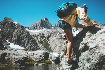 Wall Mural - Active traveler woman backpacker rock climbing and looking at stunning mountain wild beauty