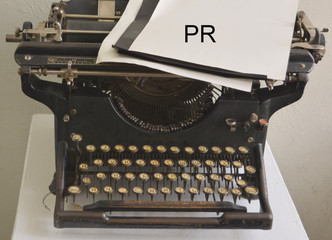 PR, an inscription on a paper lying on an old pussy typewriter. The concept of public relations in a vintage style