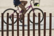 woman riding a bicycle at the beach behind a sand fence, partial view