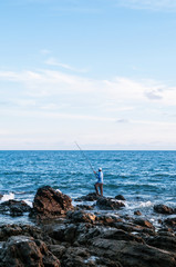 Wall Mural - Local fisherman is fishing with fishing rod in evening at Nui beach on Koh Lanta, Krabi, Thailand