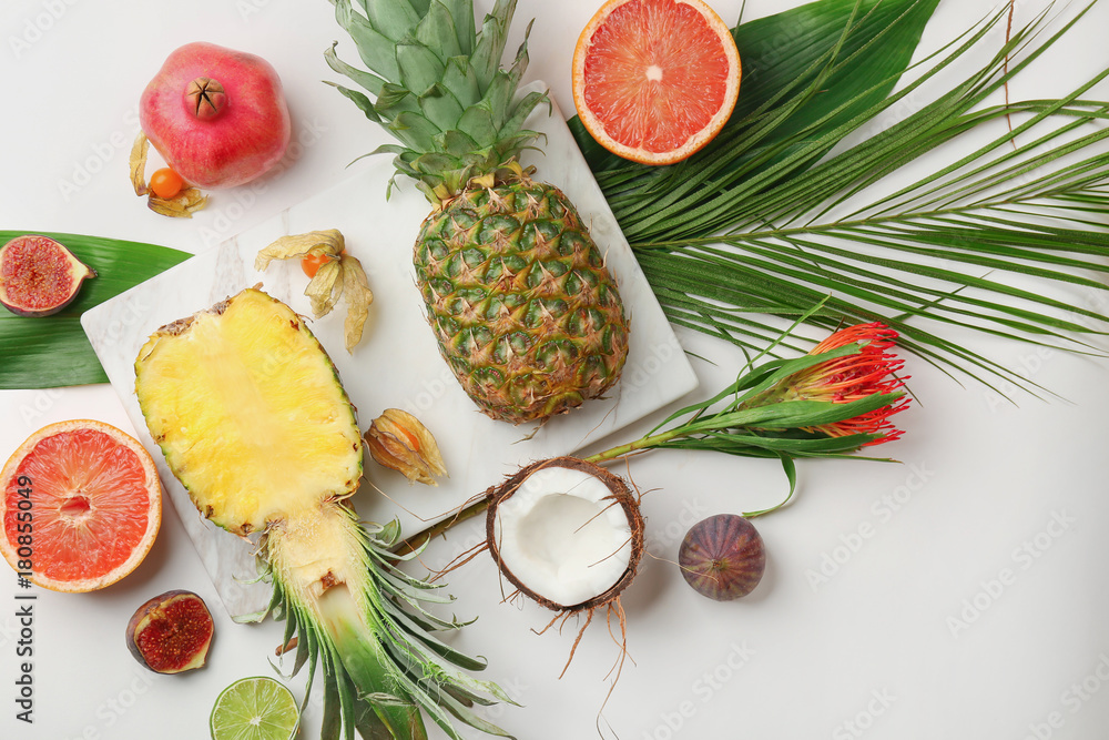 Composition with tropical leaves and exotic fruits on light background