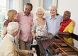 © Monkey Business - Group Of Seniors Standing By Piano And Singing Together