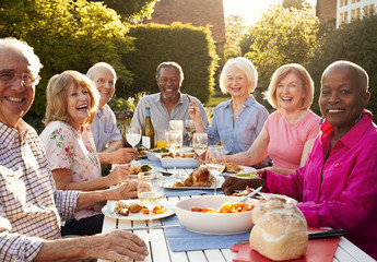 Portrait Of Senior Friends Enjoying Outdoor Dinner Party At Home