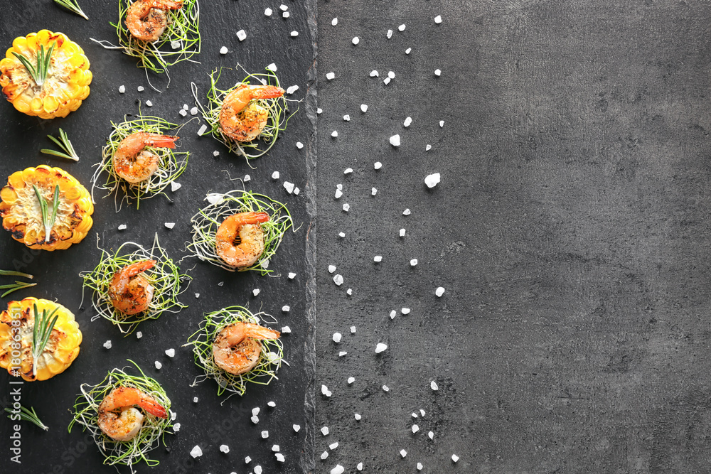 Slate plate with delicious grilled shrimps on table