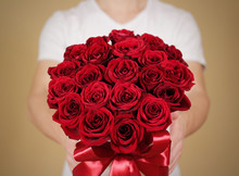 Man In White T Shirt Holding In Hand Rich Gift Bouquet Of 21 Red Roses. Composition Of Flowers In A White Hatbox. Tied With Wide Red Ribbon And Bow.