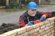 © sima - Worker examining brick wall using level tool