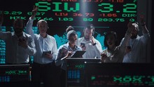 An enthusiastic stock broker team in a futuristic office full of live global market feeds.