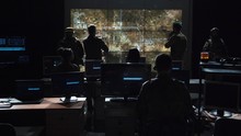 Group Of Soldiers Or Spies In Dark Room With Large Monitors And Advanced Satellite Communication Technology Launching A Missle. Includes Flashing Yellow Light.