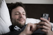 © PhotoAlto - Man reclining in bed using smart phone