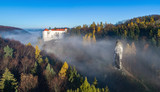 Fototapeta  - Limestone cliff Pieskowa Skala near Krakow, Poland, with isolated rock  “Maczuga Herkuklesa” (Hercules cudgel or bludgeon) and historic Renaissance castle in morning fog in fall. Aerial panorama