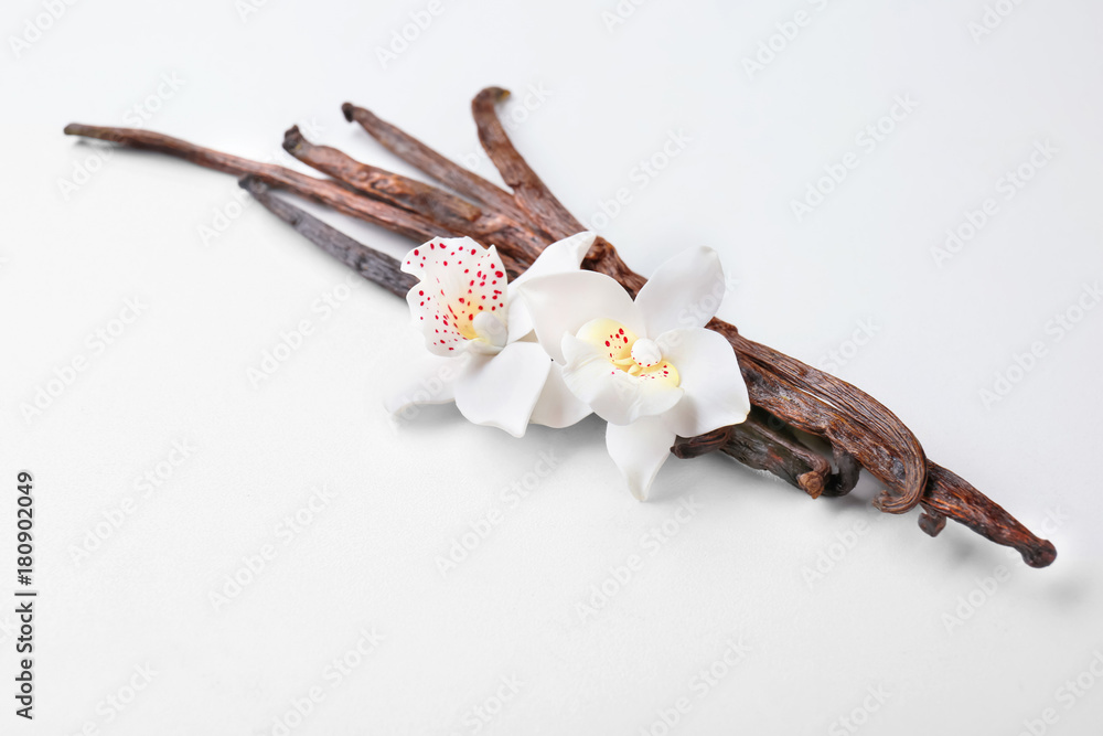 Dried vanilla pods and flowers on light background