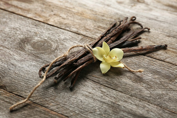 Dried vanilla pods and flower on wooden background