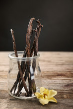 Dried Vanilla Pods In Glass Jar And Flower On Table