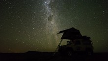 A Slow Linear Night Timelapse Of A Safari Vehicle (4x4) In An Adventurous Wild Camping Location With A Rooftop Tent Against The Milky Way And Starry Sky. 