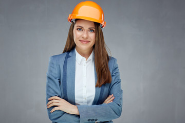 Woman builder engineer standing against gray wall with crossed arms.