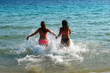 © tempora - Back view of two female friends holding hands and running through the sea.
