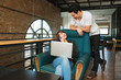 © supong32 - Couple lover talk together while woman on the phone and sits on armchair at home office,