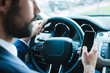 © MARIIA - looking best way to get to office. Rear view of young businessman using his smart phone while sitting in car
