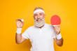 © deagreez - Competetive emotional cool active goofy comic grey haired grandpa with humor grimace and beaming grin, with table tennis equipment. Healthcare, weight loss, bodycare lifestyle