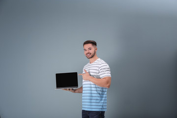 Canvas Print - Young man with laptop against light background