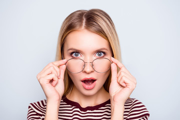 Wow! I don't believe you! Close up portrait of shocked astonished woman with open mouth and big eyes, she is touching her spectacles