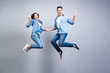 © deagreez - Concept of freedom, carelessness, good mood and enjoying life. Totally glad and happy lovers in jeans denim casual clothes are jumping up and showing v-sign, they are isolated on grey background.