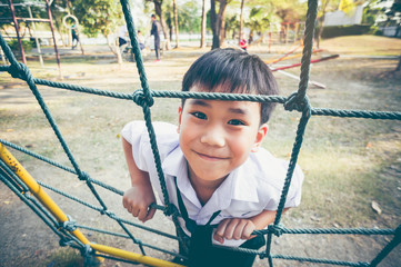 Wall Mural - Asian child climbing in a rope at children playground. Vintage tone.