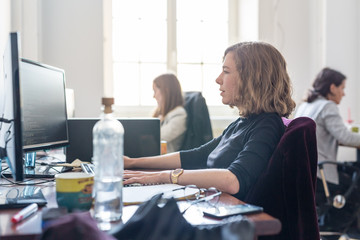 Women in startup business and entrepreneurship. Yound devoted female AI programmers and IT software developers team programming on desktop computer in startup company share office space.