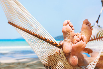 family relaxing on the beach in hammock, exotic holidays travel, closeup of feet