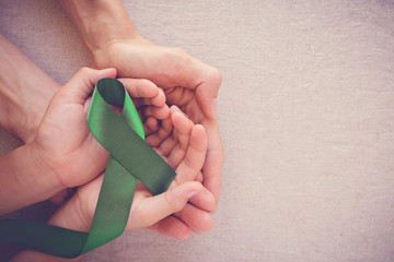 adult and child hands holding Green Ribbon, cancer awareness, Liver, Gallbladder Bile Duct cancer awareness, Hepatitis B awareness