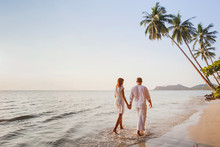 Romantic Young Couple Walking Together On Beautiful Exotic Tropical Beach At Sunset