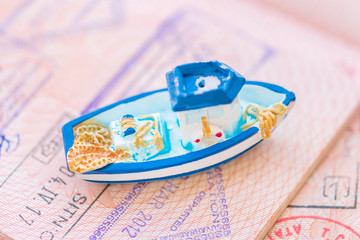 Wall Mural - Small blue toy boat lying on the passport page with visa stamps