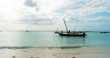 Wall Mural - Old rustic fishing boat sitting in the ocean, calm and still turquoise waters, zanzibar