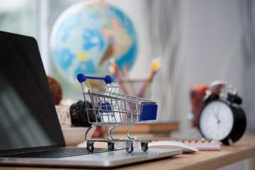 Mini shopping cart on computer laptop. Business concept.