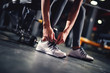 © dusanpetkovic1 - Woman's hand tying shoelaces in the gym near the dumbbells before exercising close up.