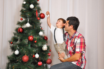 Young father with decorating Christmas tree with his son. Family together for holidays