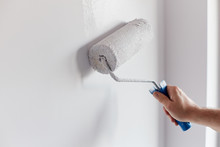 Male Hand Painting Wall With Paint Roller. Painting Apartment, Renovating With White Color Paint