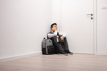 Sticker - Pensive teenage student sitting in a corner indoors