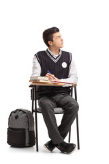 Wall Mural - Teenage student seated in a school chair taking notes