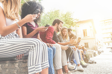 Wall Mural - Diverse culture friends using smartphones outdoor - Group of happy people having fun with technology trends - Youth, new generation addiction and friendship concept - Main focus on left bearded man