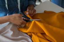 Mid Section Of Female Fashion Designer Cutting Fabric