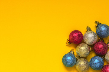 Studio shot of Christmas decorations.Studio shot of Christmas ornaments against a yellow background. Christmas Background. Colored Christmas decoration ball on a yellow background with space for text.