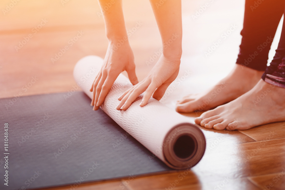 Yoga. Close-up woman folding roll fitness or yoga mat after working out home in living room. Concept healthy life. - obrazy, fototapety, plakaty 
