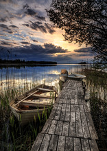 Small Boats At A Wooden Jetty With Sunset In The Background