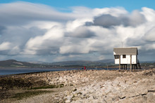An Elevated Hut Looks Out Over A Pebble Beach Towards The Morecambe Bay, Lancashire With Rolling Clouds Above. This Is A Panorama Stitch Of 5 Images.